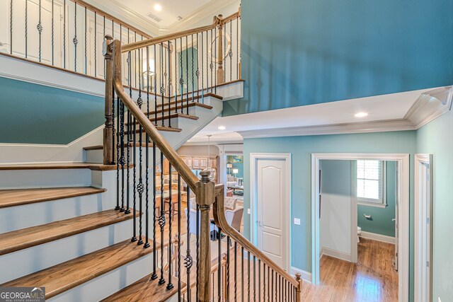 stairs with ornamental molding and hardwood / wood-style flooring