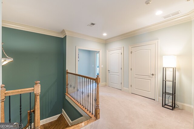 hallway with ornamental molding and light carpet