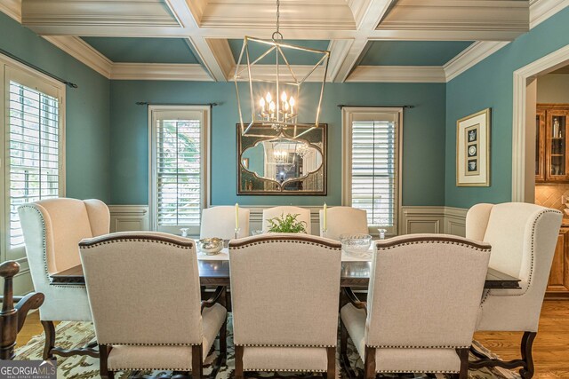 dining area with coffered ceiling, wood-type flooring, crown molding, and a notable chandelier