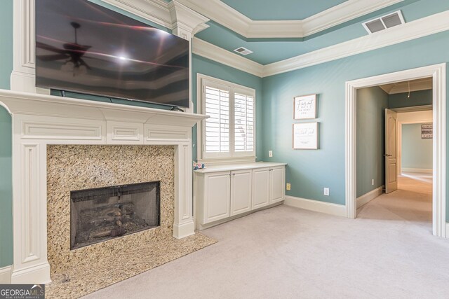 unfurnished living room with crown molding, a premium fireplace, ceiling fan, and light colored carpet