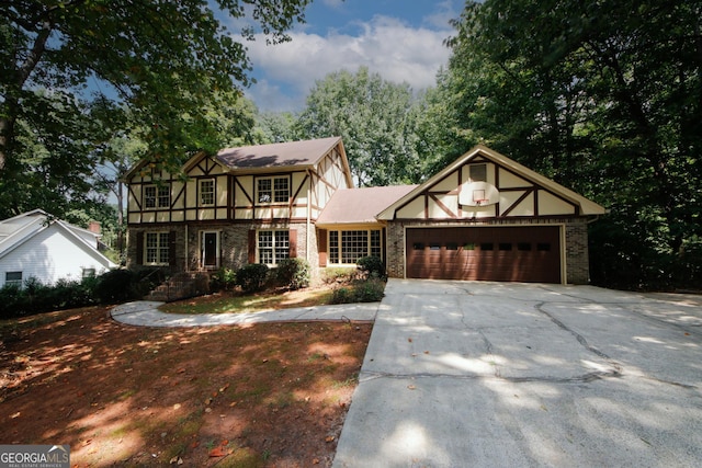 tudor home with a garage, stone siding, and driveway