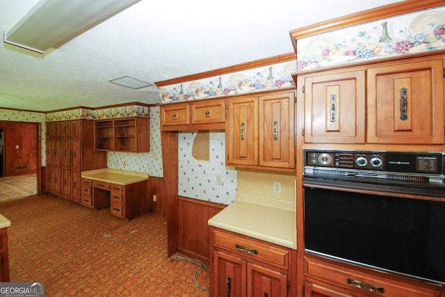 kitchen featuring ornamental molding, light countertops, oven, and wallpapered walls