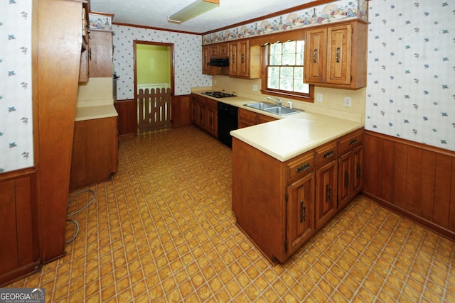 kitchen featuring light countertops, wainscoting, a sink, black appliances, and wallpapered walls