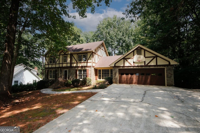 tudor home featuring concrete driveway, brick siding, an attached garage, and stucco siding