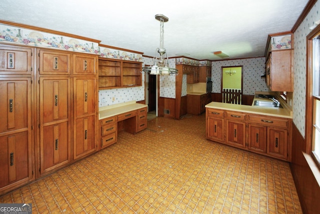 kitchen with pendant lighting, light countertops, built in study area, wainscoting, and wallpapered walls