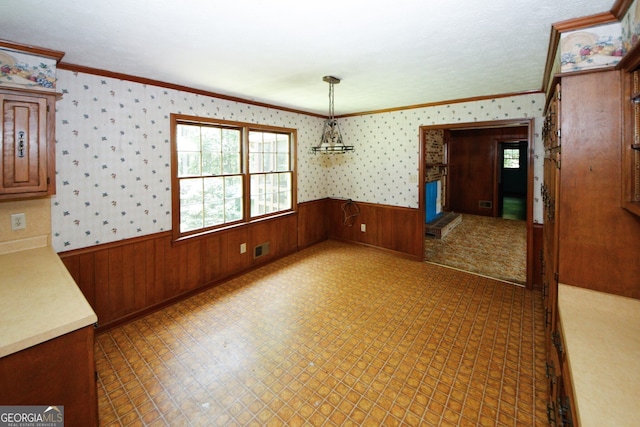 unfurnished dining area featuring a wainscoted wall, visible vents, tile patterned floors, wallpapered walls, and crown molding