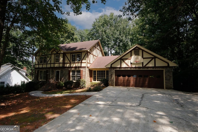 english style home featuring a garage, driveway, brick siding, and stucco siding