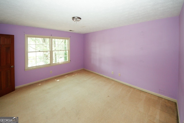 empty room featuring light carpet, baseboards, and a textured ceiling