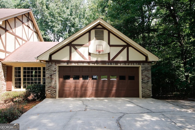 view of front of home with a garage, brick siding, driveway, and stucco siding