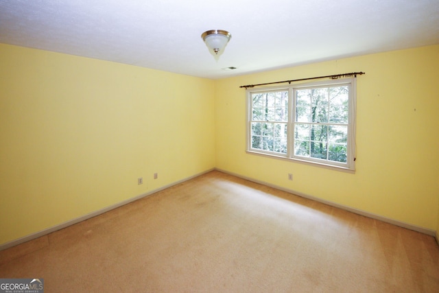 unfurnished room with light carpet and baseboards