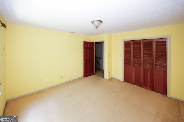 unfurnished bedroom featuring baseboards, a closet, and light colored carpet