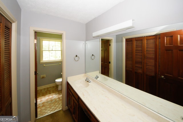 bathroom with toilet, a textured ceiling, a closet, and vanity