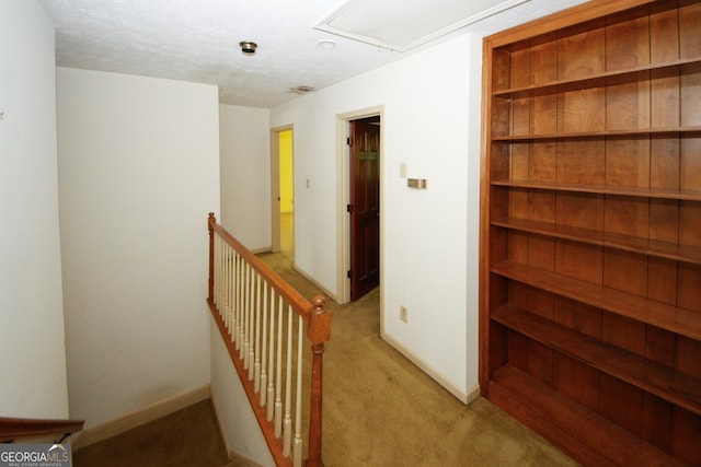 corridor featuring light carpet, a textured ceiling, an upstairs landing, and baseboards