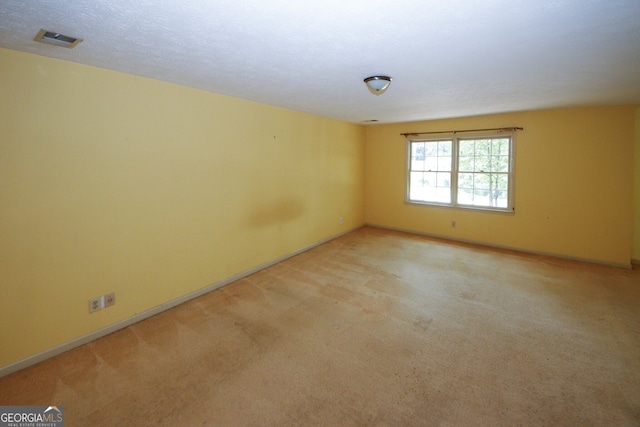 unfurnished room featuring visible vents, a textured ceiling, and light colored carpet