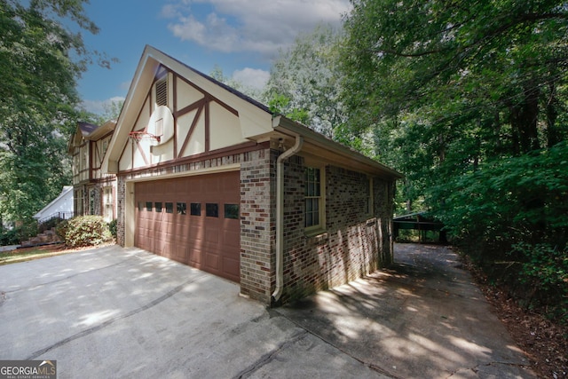 view of side of home with a garage, brick siding, driveway, and stucco siding