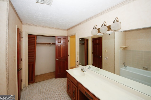 full bathroom with a textured ceiling, vanity, visible vents, a bath, and a walk in closet