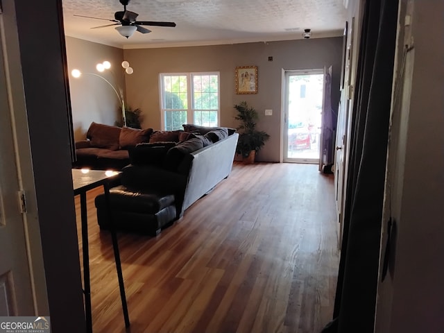 living room featuring ceiling fan, a textured ceiling, crown molding, and hardwood / wood-style flooring