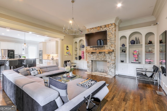 living room featuring built in shelves, a chandelier, a stone fireplace, dark hardwood / wood-style flooring, and ornamental molding