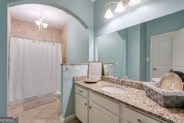 bathroom featuring tile patterned flooring, toilet, an inviting chandelier, and vanity