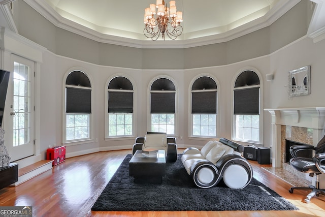 living room with an inviting chandelier, built in shelves, crown molding, hardwood / wood-style flooring, and a premium fireplace