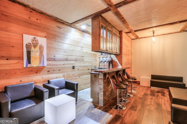 interior space featuring wood walls, beamed ceiling, wood-type flooring, bar, and wooden ceiling