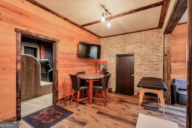 dining area with wood-type flooring, wood walls, and brick wall