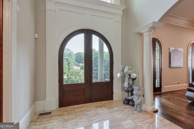 entrance foyer featuring light hardwood / wood-style floors, ornate columns, crown molding, and french doors