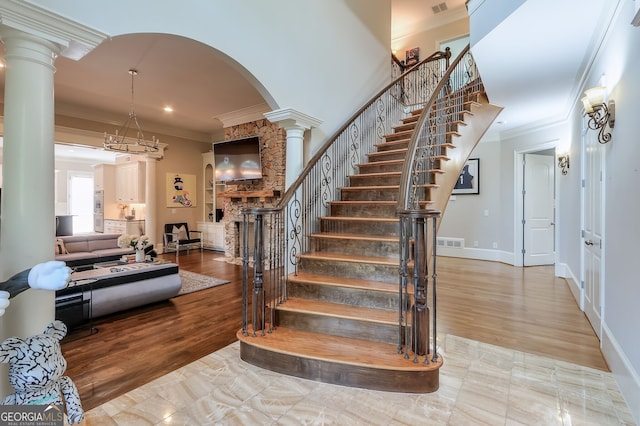 stairway featuring crown molding, decorative columns, and wood-type flooring