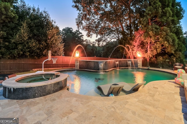 pool at dusk with an in ground hot tub, a patio, and pool water feature