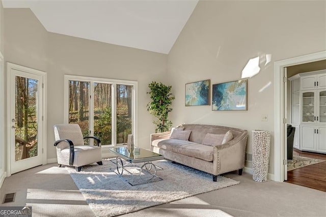 living room with light colored carpet and high vaulted ceiling