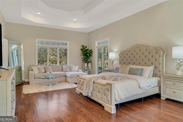 bedroom with dark hardwood / wood-style floors and a raised ceiling