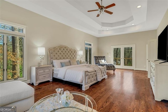 bedroom with access to exterior, ceiling fan, french doors, dark hardwood / wood-style flooring, and a tray ceiling