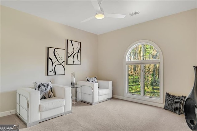 living area with ceiling fan, plenty of natural light, and light colored carpet