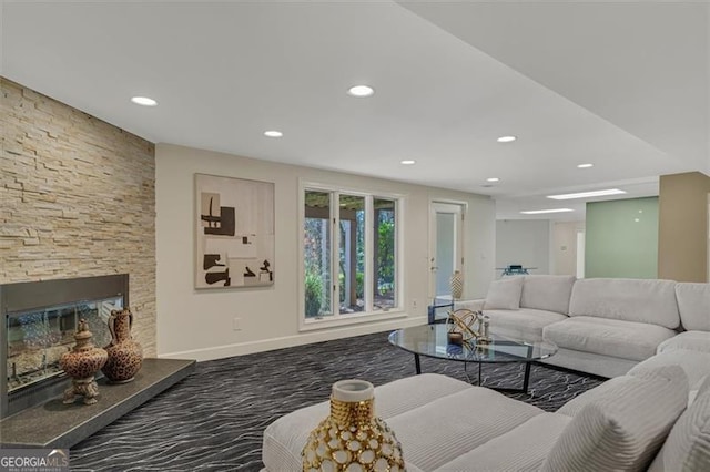 carpeted living room featuring a stone fireplace