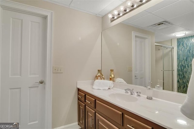 bathroom featuring a paneled ceiling, vanity, and an enclosed shower