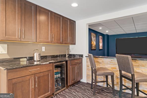 bar featuring sink, wine cooler, and dark stone counters