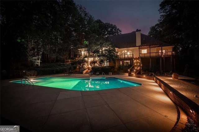 pool at dusk with a patio area