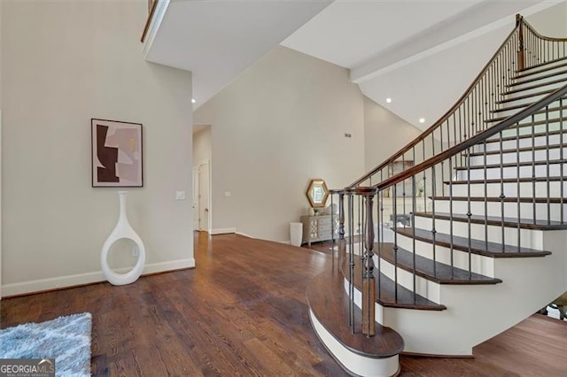 stairs with hardwood / wood-style floors, beam ceiling, and high vaulted ceiling