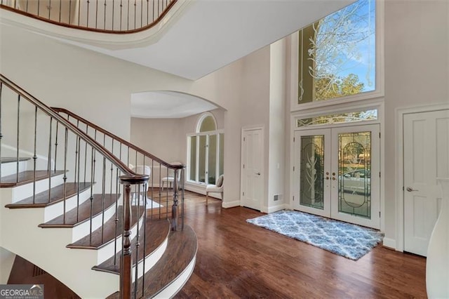 entrance foyer featuring dark hardwood / wood-style flooring, a towering ceiling, and french doors