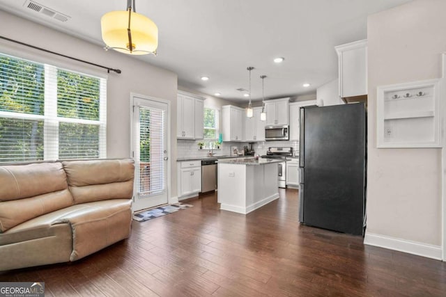 kitchen with a center island, hanging light fixtures, appliances with stainless steel finishes, open floor plan, and white cabinetry