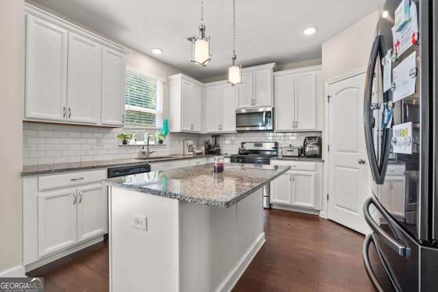 kitchen with white cabinets, light stone counters, stainless steel appliances, and a center island