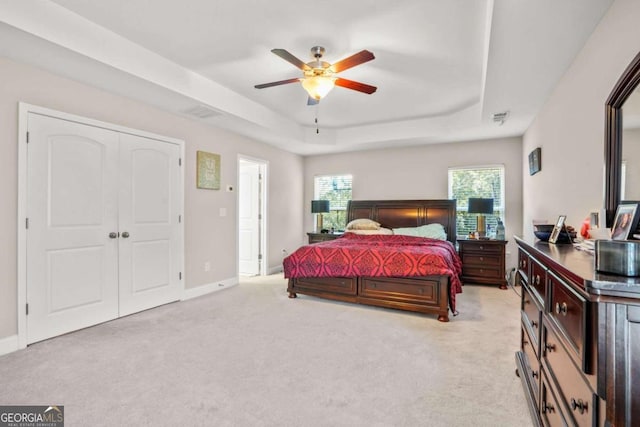 bedroom with visible vents, baseboards, a raised ceiling, light colored carpet, and ceiling fan