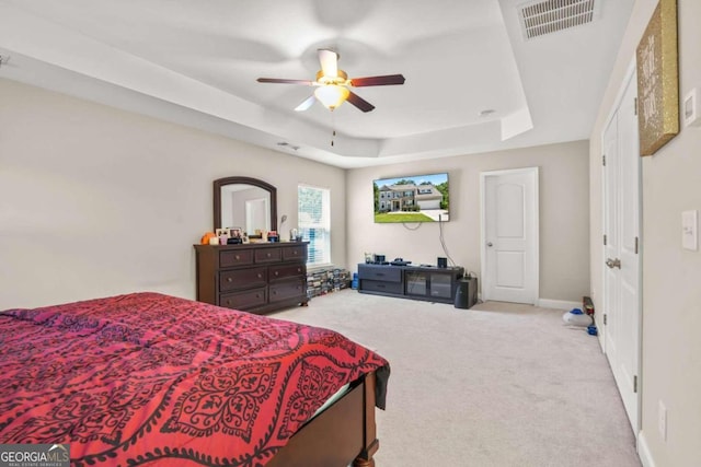 bedroom featuring light colored carpet, a ceiling fan, baseboards, visible vents, and a raised ceiling