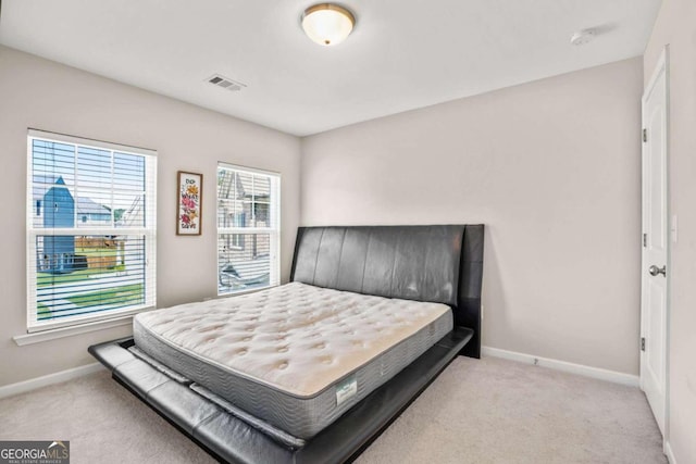 bedroom with visible vents, light carpet, and baseboards