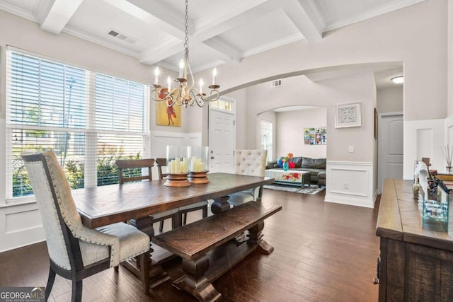 dining room featuring arched walkways, a decorative wall, visible vents, beam ceiling, and dark wood-style floors