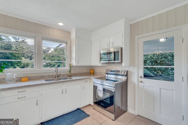 kitchen with light stone countertops, white cabinetry, light tile patterned floors, sink, and range with electric cooktop