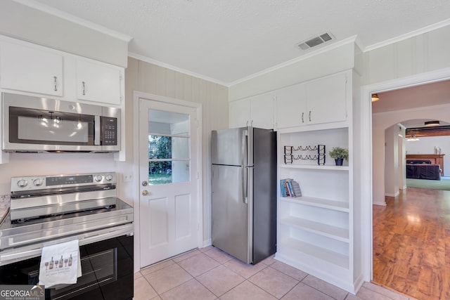 kitchen featuring a textured ceiling, white cabinetry, crown molding, light wood-type flooring, and stainless steel appliances