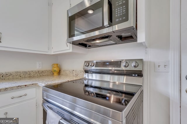 kitchen featuring white cabinets, stainless steel appliances, and light stone countertops