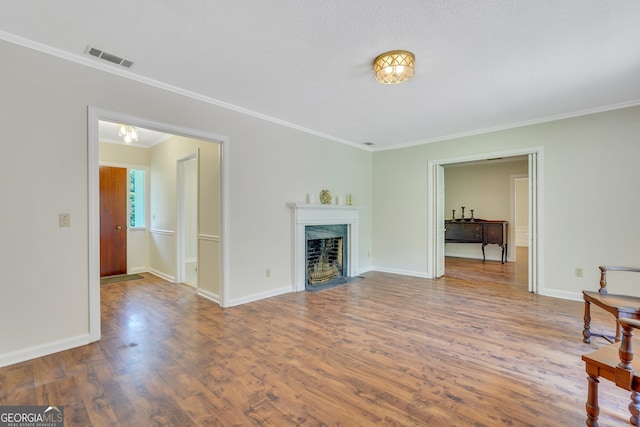 living room with a fireplace, a textured ceiling, ornamental molding, and hardwood / wood-style flooring