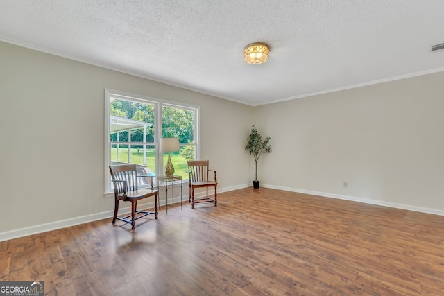 sitting room featuring hardwood / wood-style flooring, a textured ceiling, and ornamental molding